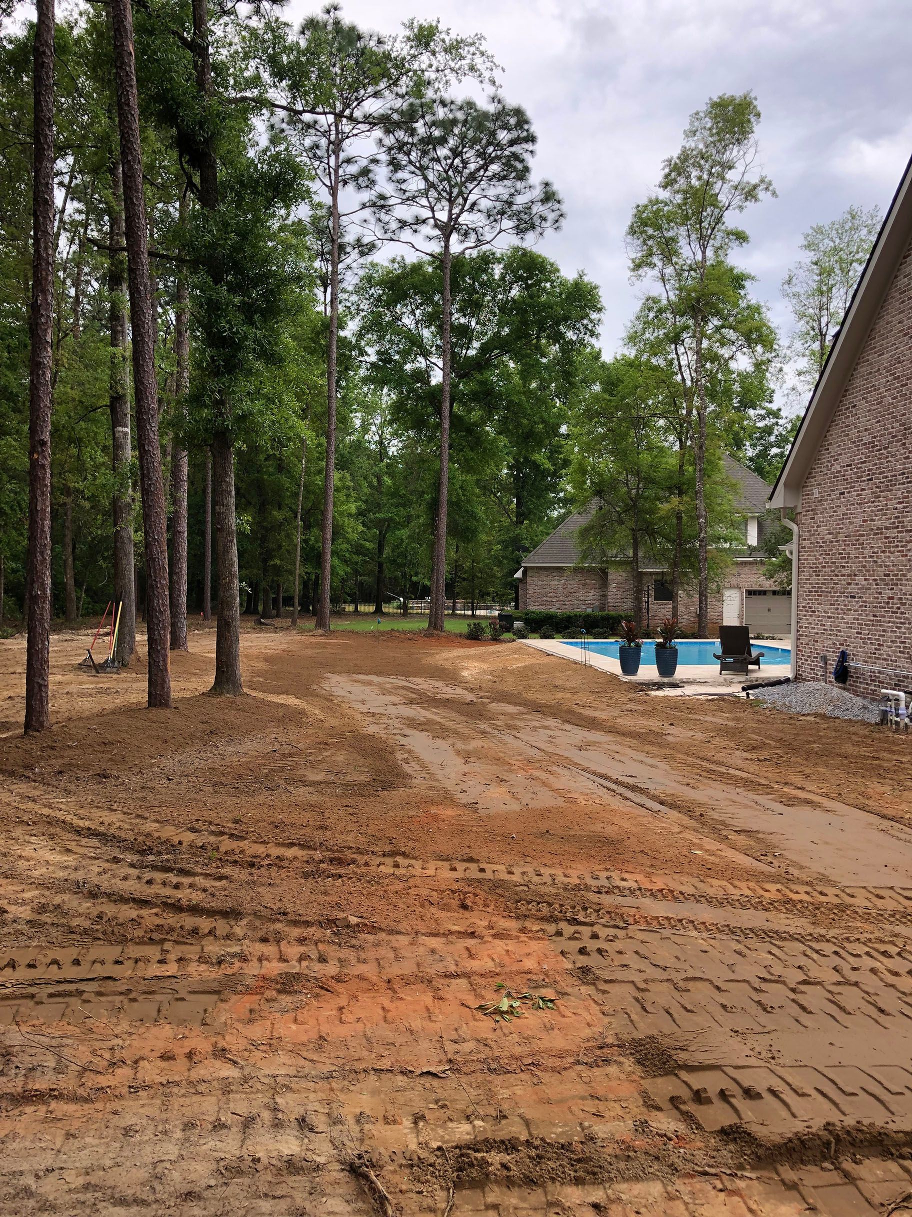 A dirt road leading to a house with a pool in the background.