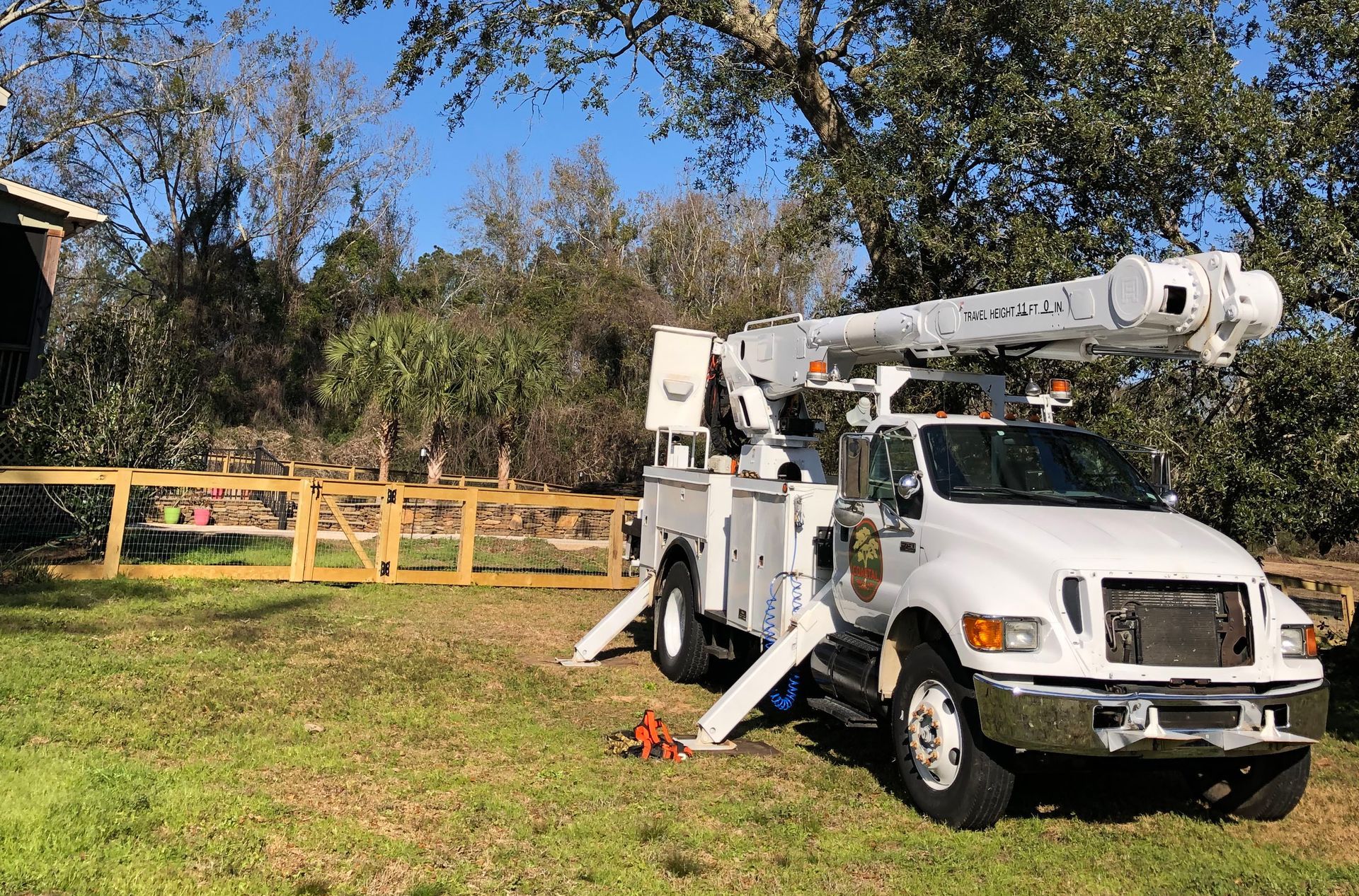 A white truck with a crane on top of it is parked in a grassy field.