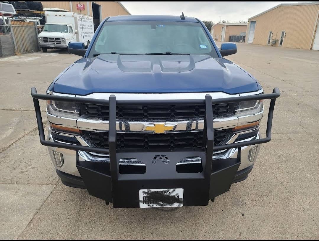 A blue truck with a black bumper is parked in a parking lot.