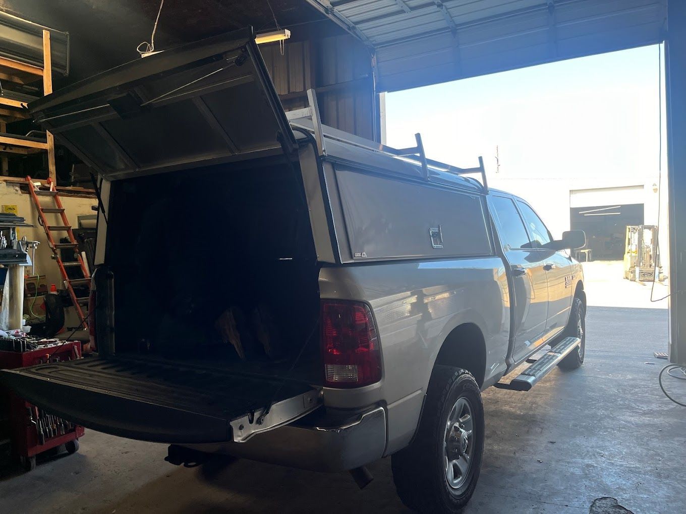 A truck with a canopy on top of it is parked in a garage.