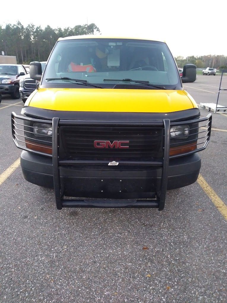 A yellow gmc van is parked in a parking lot