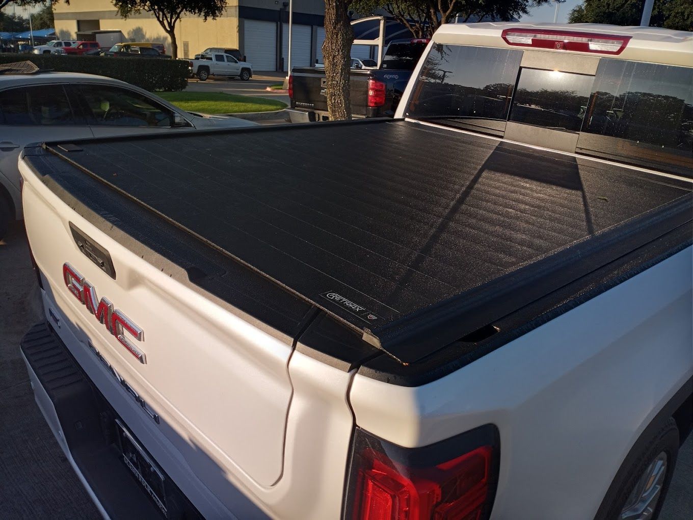 A white gmc truck with a black bed cover