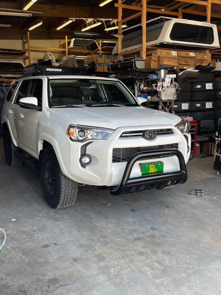 A white toyota 4runner is parked in a garage.
