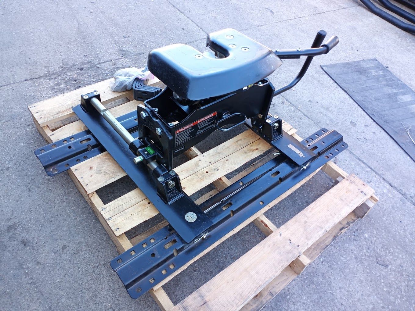 A trailer hitch is sitting on top of a wooden pallet