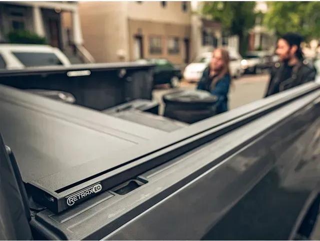 A man and a woman are standing in the back of a truck.