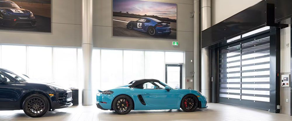 A blue car is parked in a showroom next to a black car