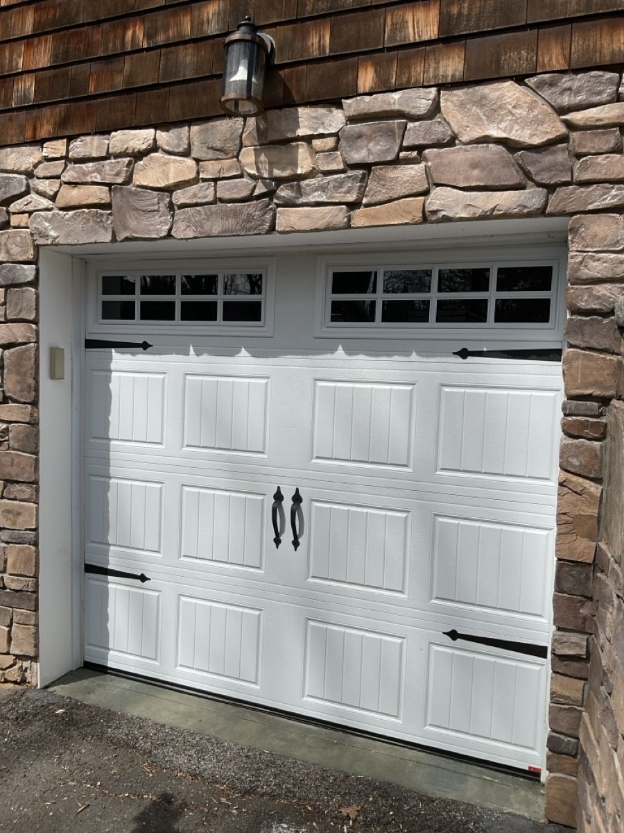 A white garage door is sitting in front of a stone wall.