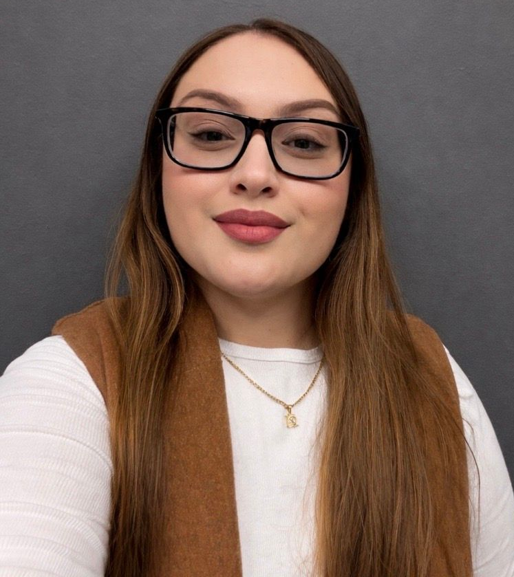 The woman is wearing glasses and a green sweater.