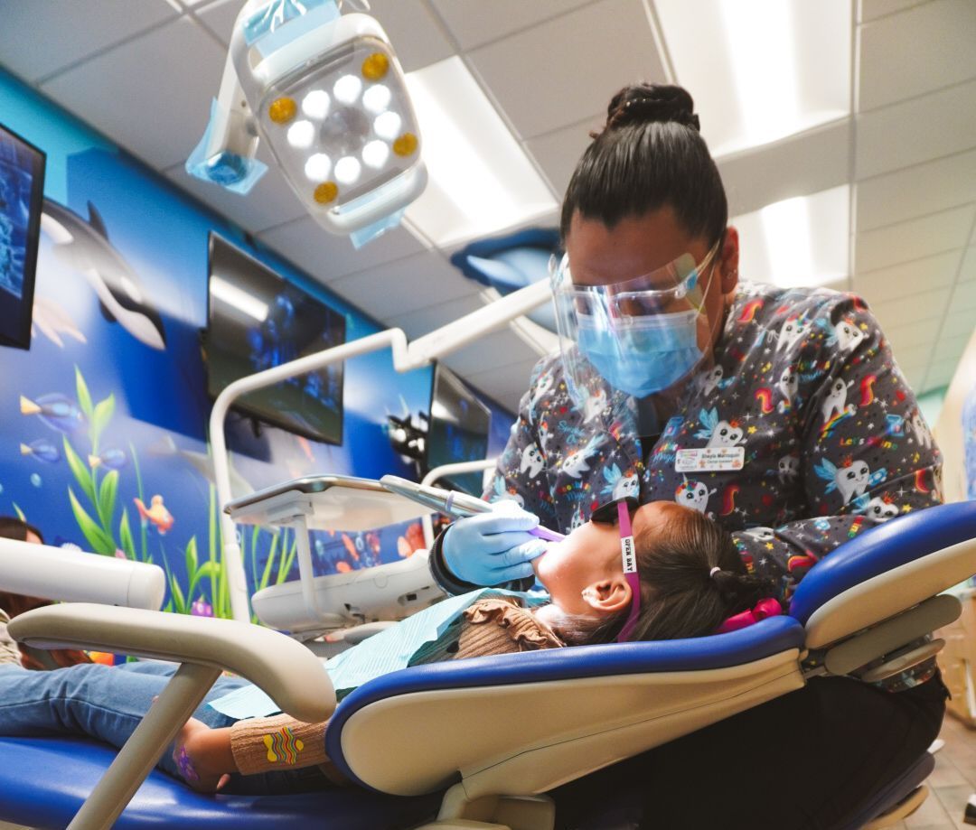 Dark haired woman doing dental work on small dark haired child