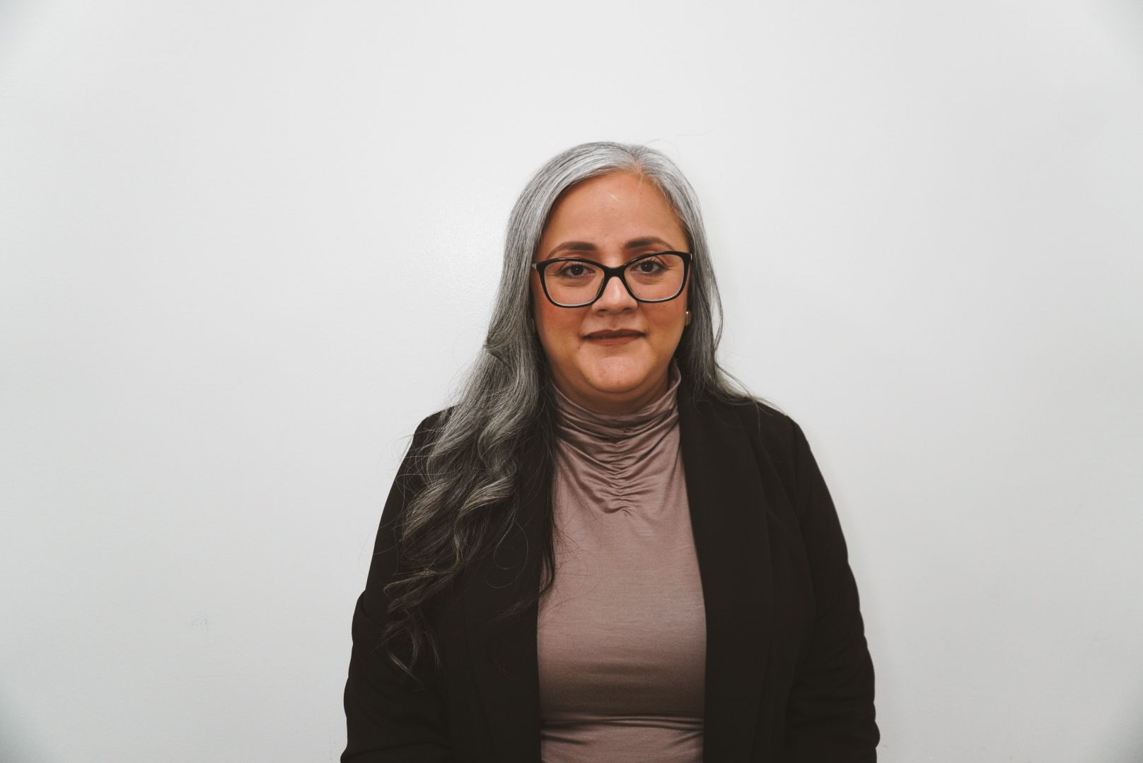 A woman wearing glasses and a black shirt is smiling for the camera.