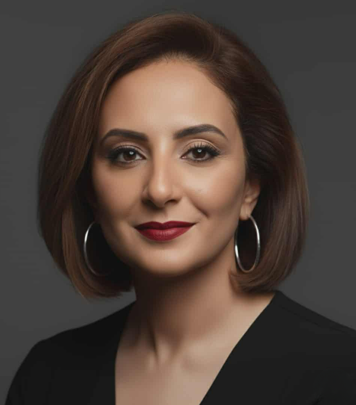 A woman wearing a black jacket and a white shirt is smiling for the camera.