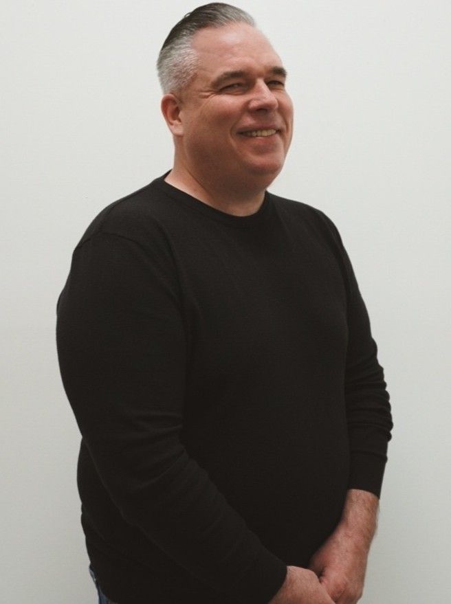 A man wearing a purple polo shirt with a tattoo on his arm