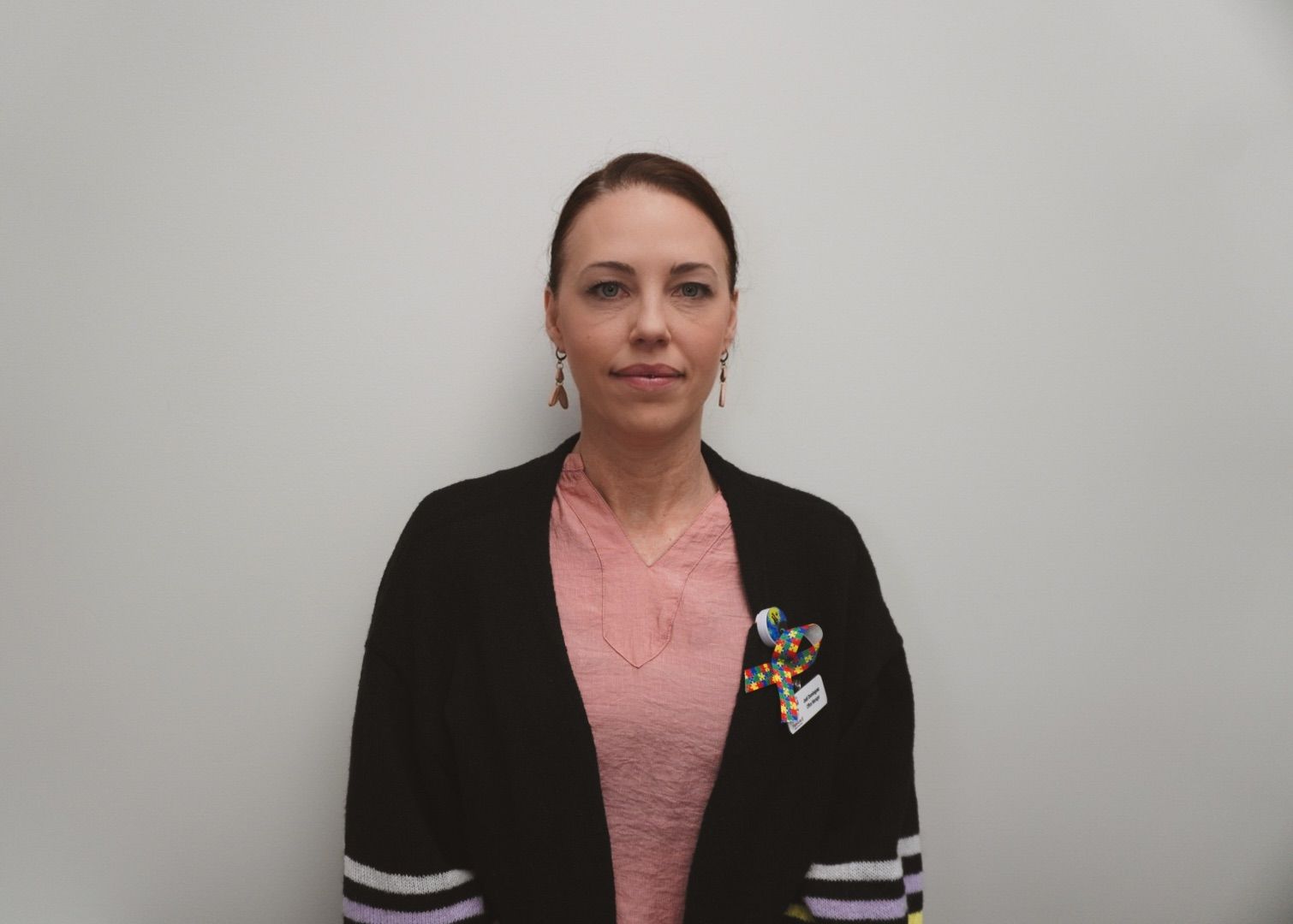 A woman wearing a blue shirt and a black cardigan is smiling for the camera.
