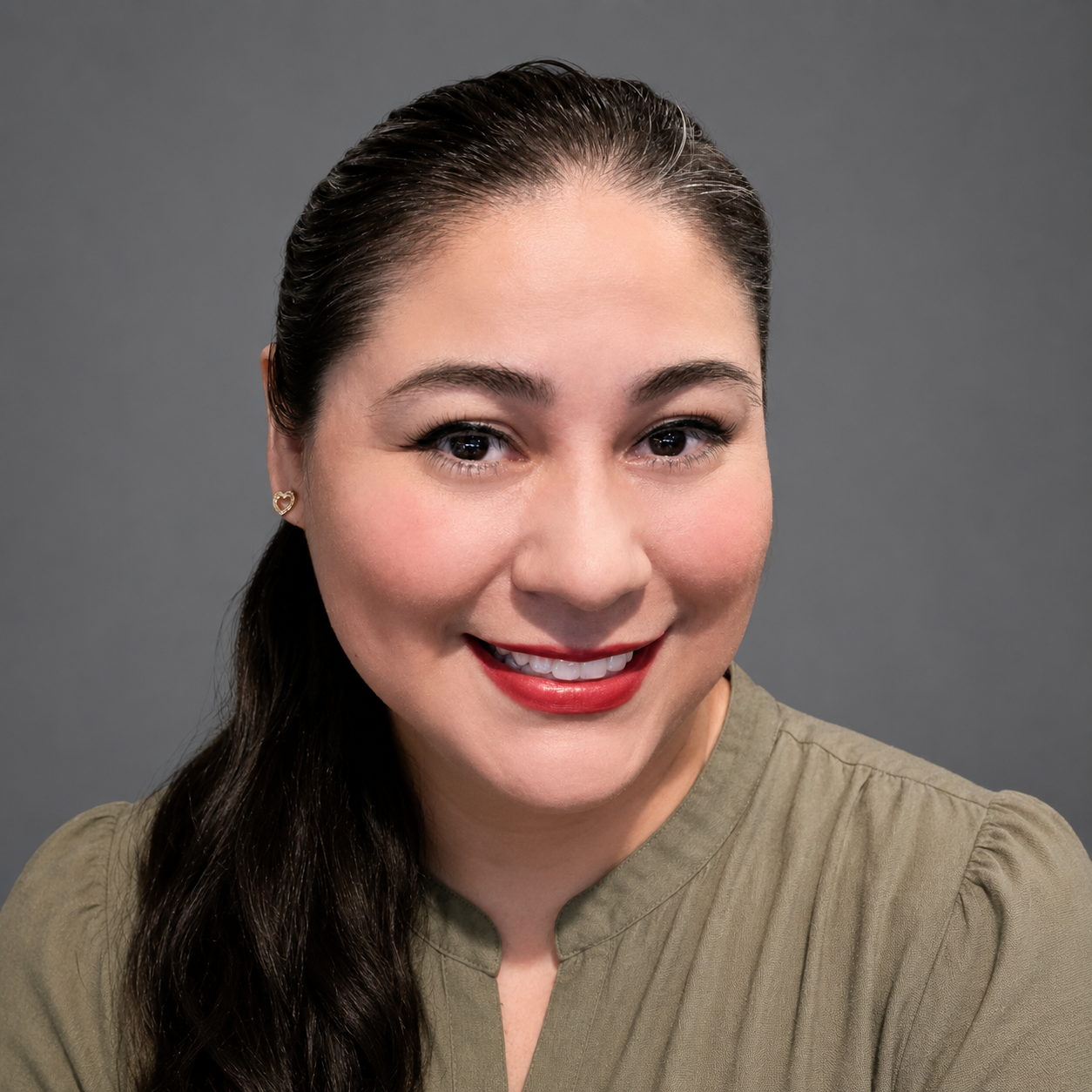 A woman with curly hair is wearing a black shirt and a grey jacket.