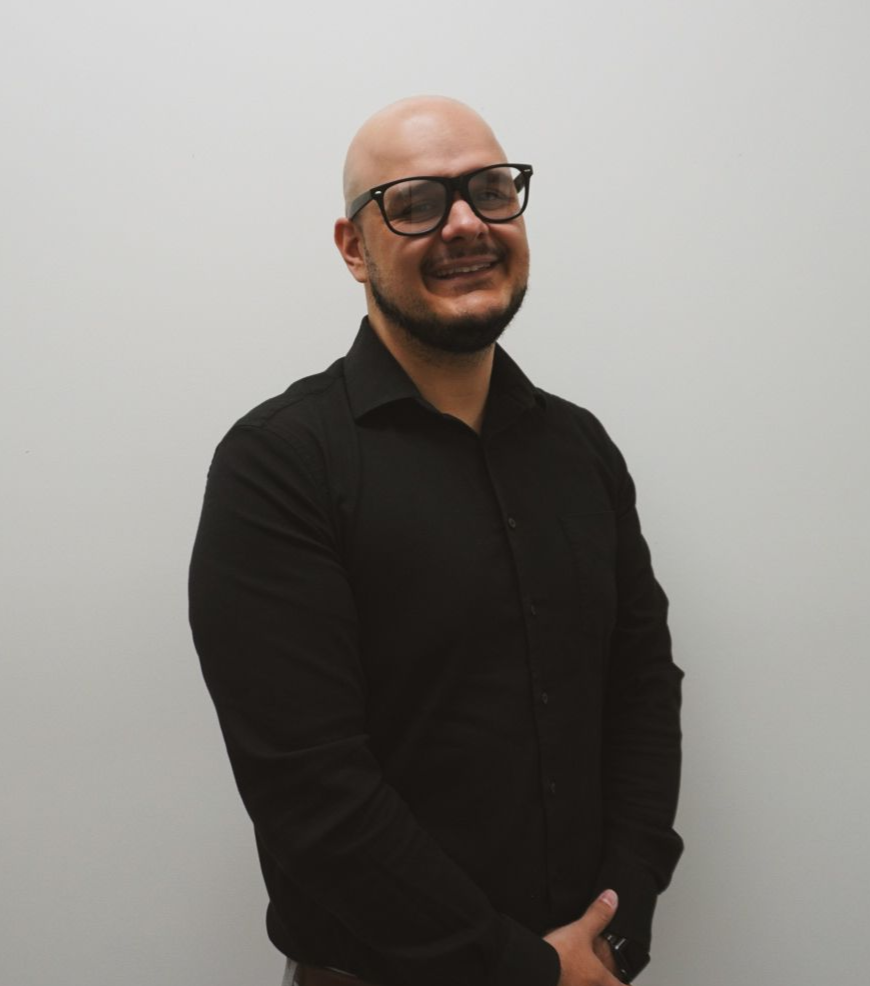 A woman with curly hair is wearing a black shirt and a grey jacket.