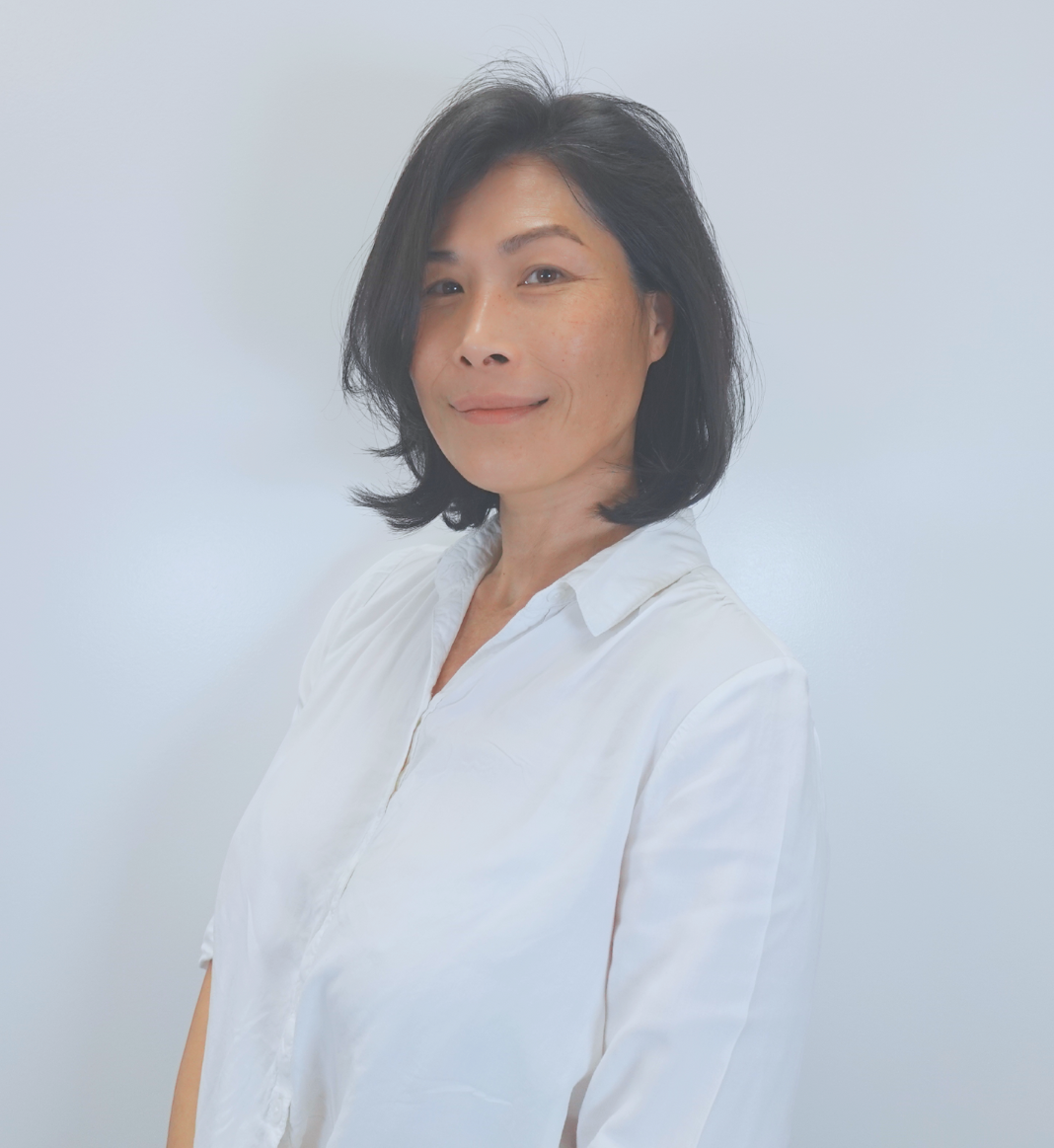 A woman with gray hair and a black shirt is smiling for the camera.