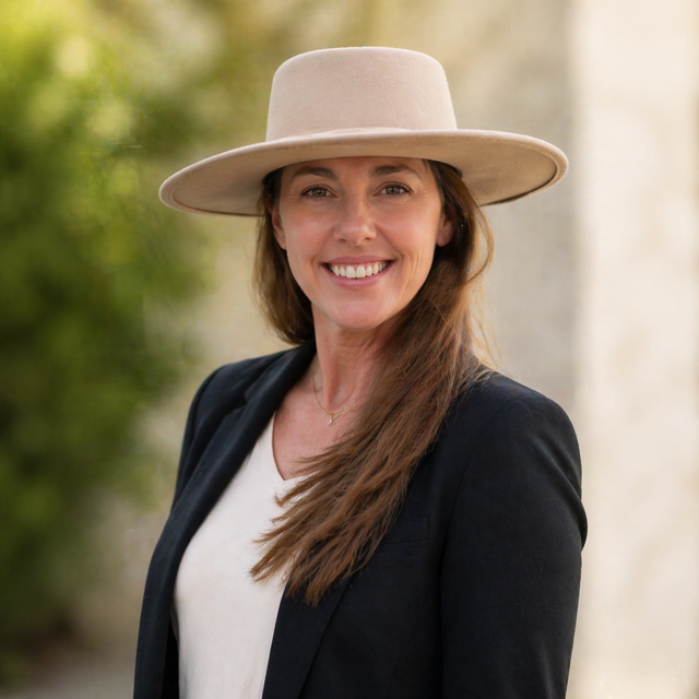 A woman wearing a blue shirt and a black cardigan is smiling for the camera.