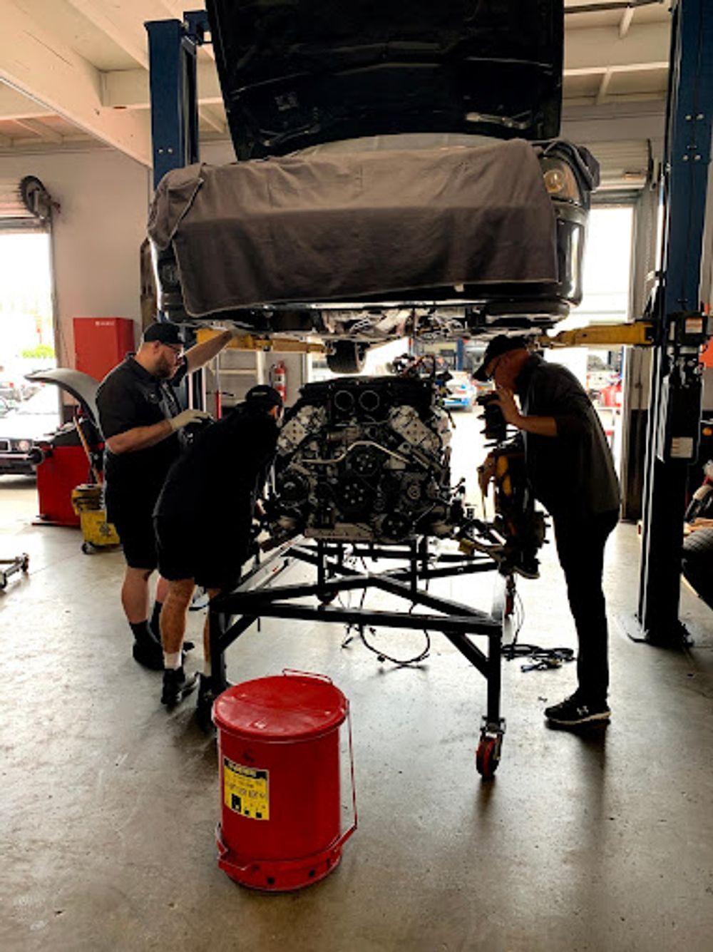 A group of men are working on a car engine in a garage.