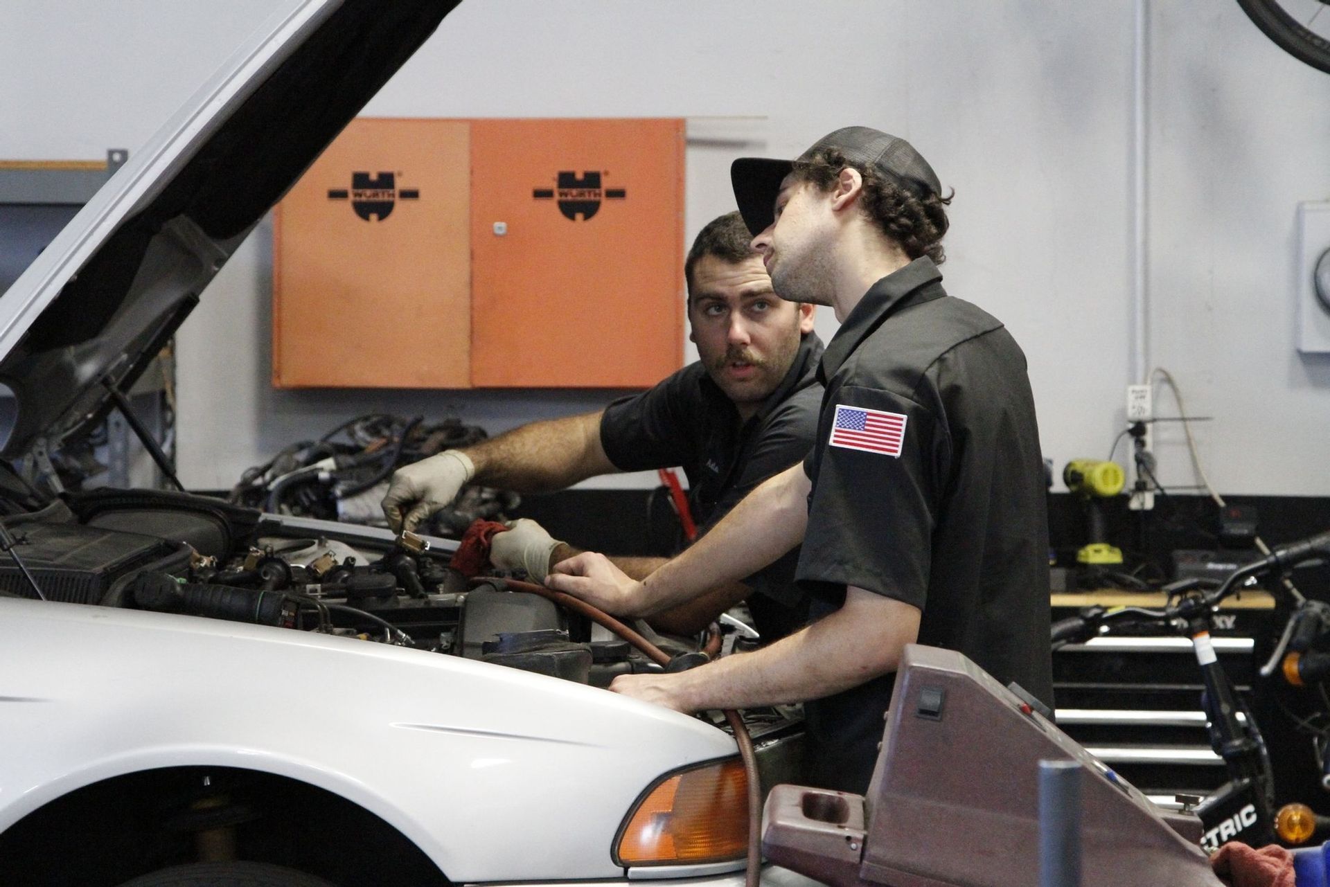 Two men are working on a car in a garage.