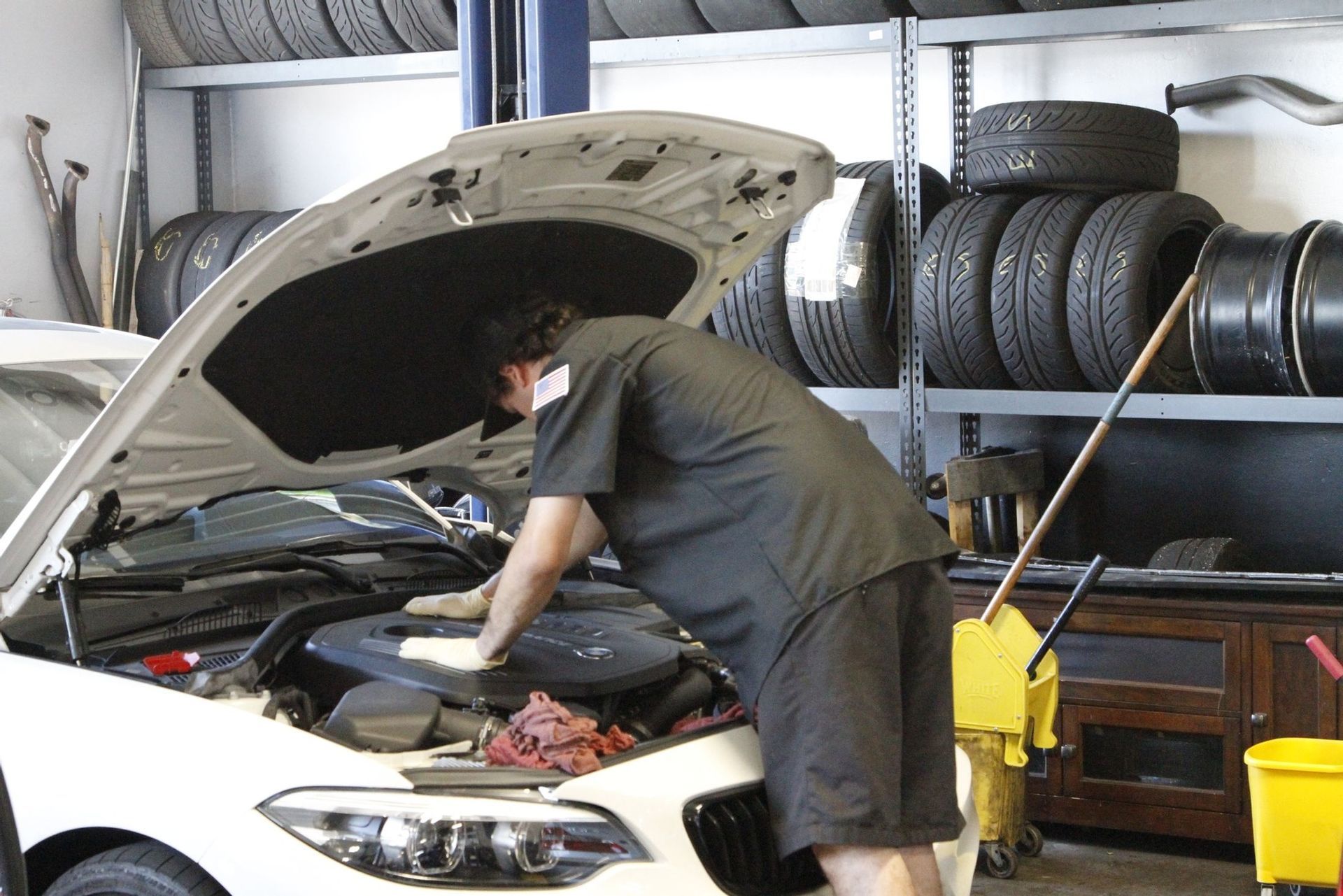 A man is working on a car in a garage with the hood open