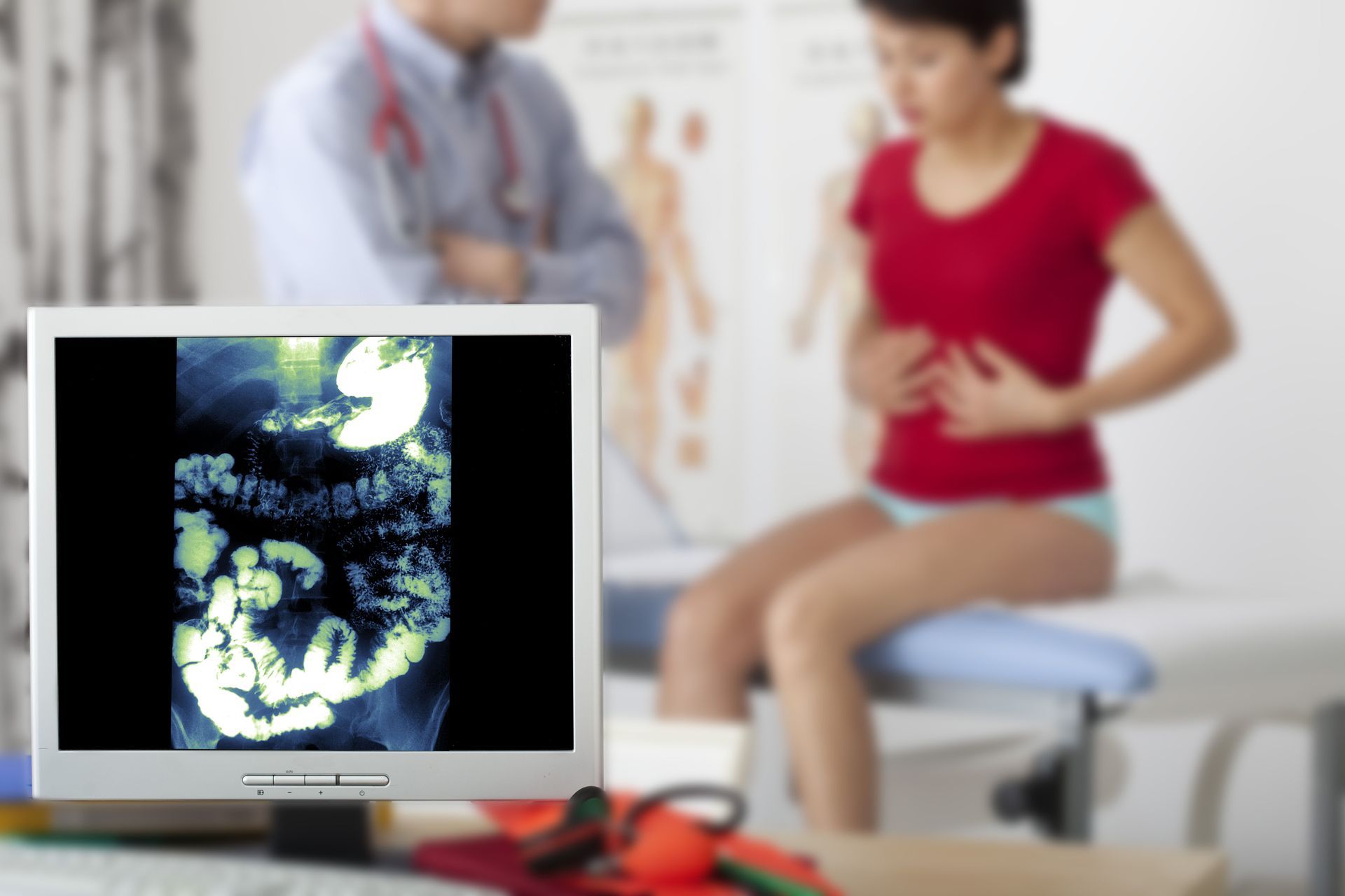 Ultrasound monitor showing fetus, with clinician and seated patient in a medical exam room