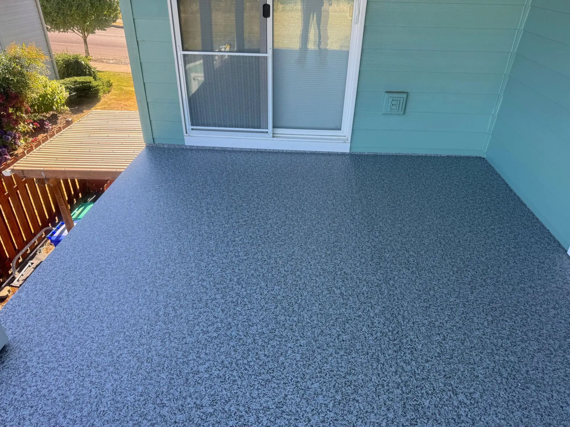 Small balcony with gray pebble-textured floor, light blue walls, and a screened sliding door.