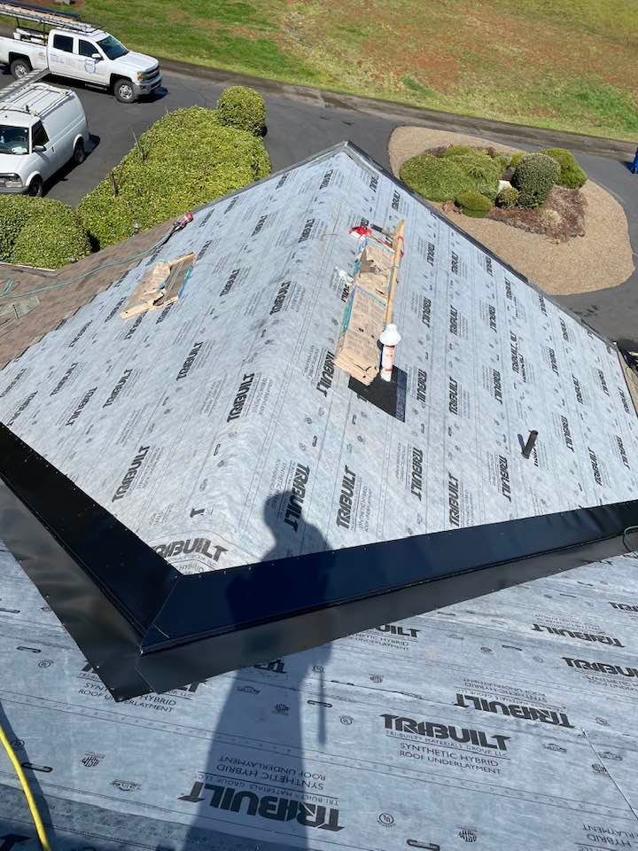 Roof under construction with gray underlayment, vents, and a clear sky view from above