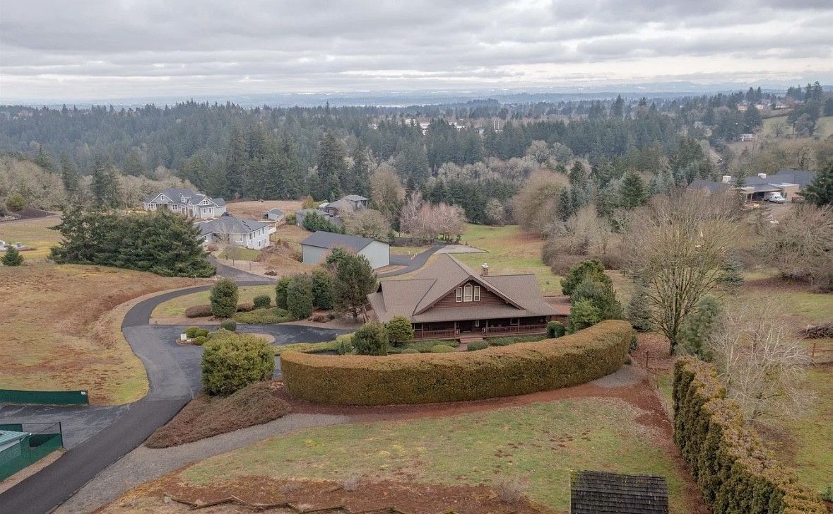Overcast suburban hillside with homes, winding roads, and autumn-colored trees.