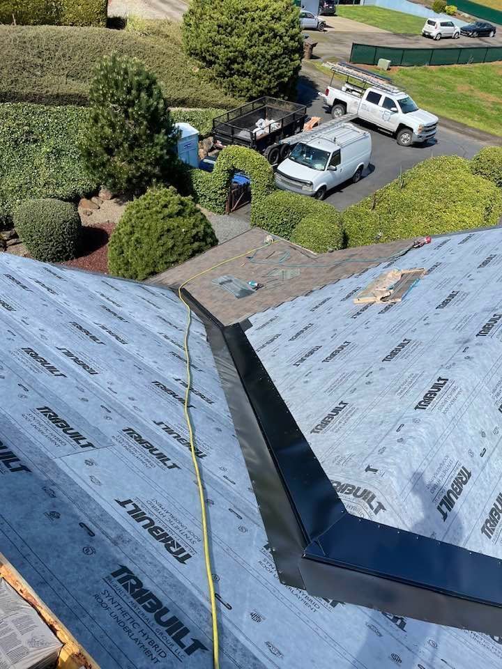 Roof under repair with gray underlayment, taped seam, and parked vehicles below