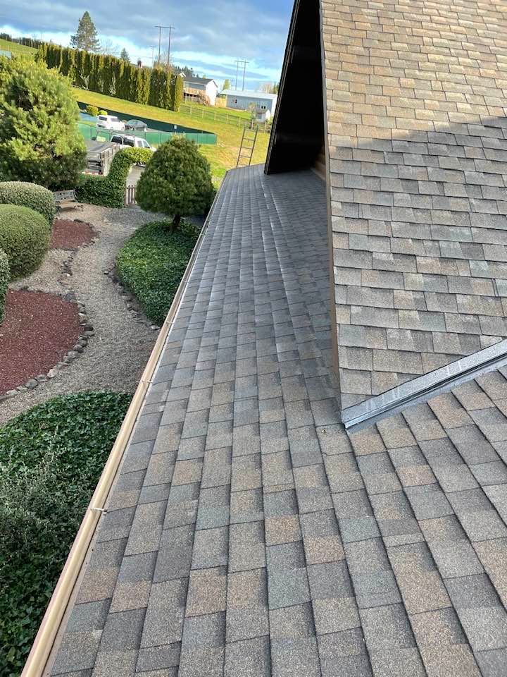 Steep shingled roof beside a landscaped garden with curving gravel paths and trimmed shrubs