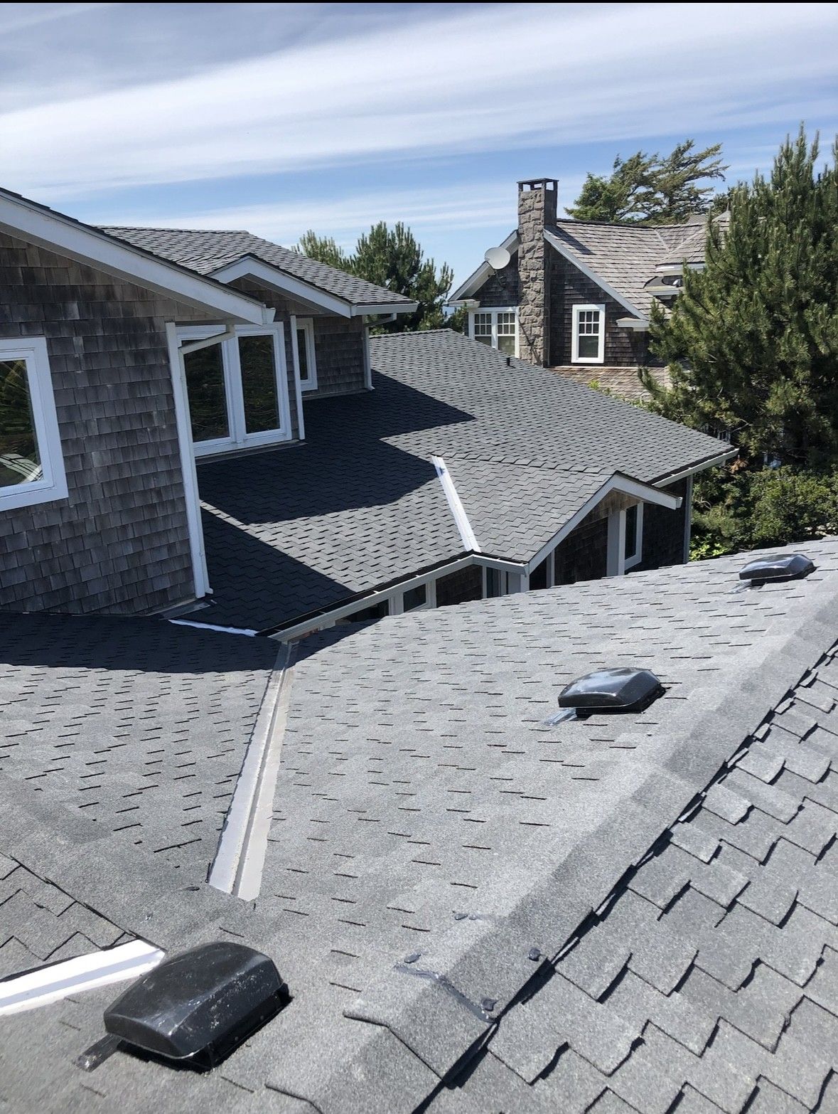 Slate shingle rooftops with skylights and chimneys on a house under a blue sky