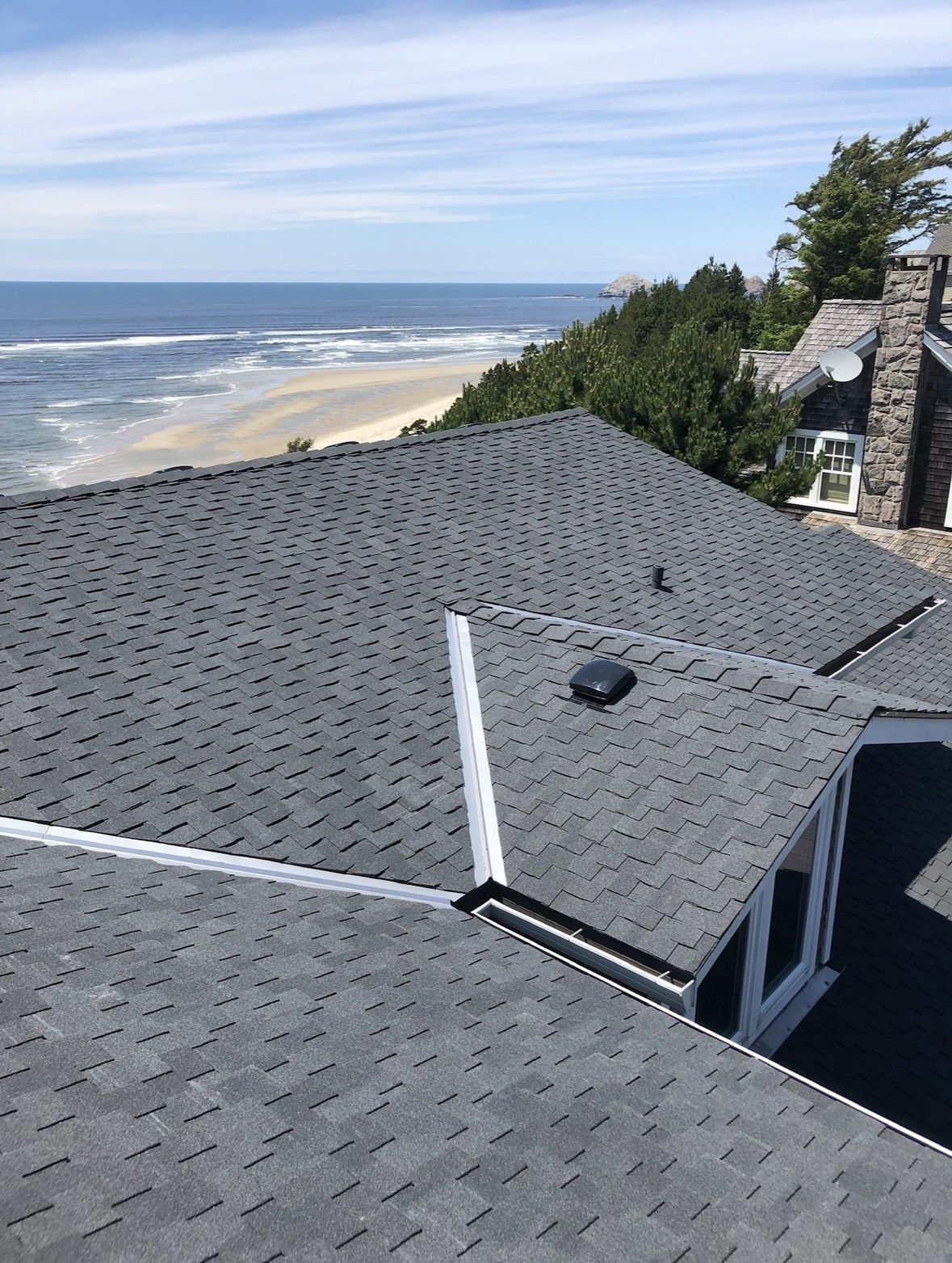 Gray shingled rooftop overlooking the ocean and sandy beach on a sunny day
