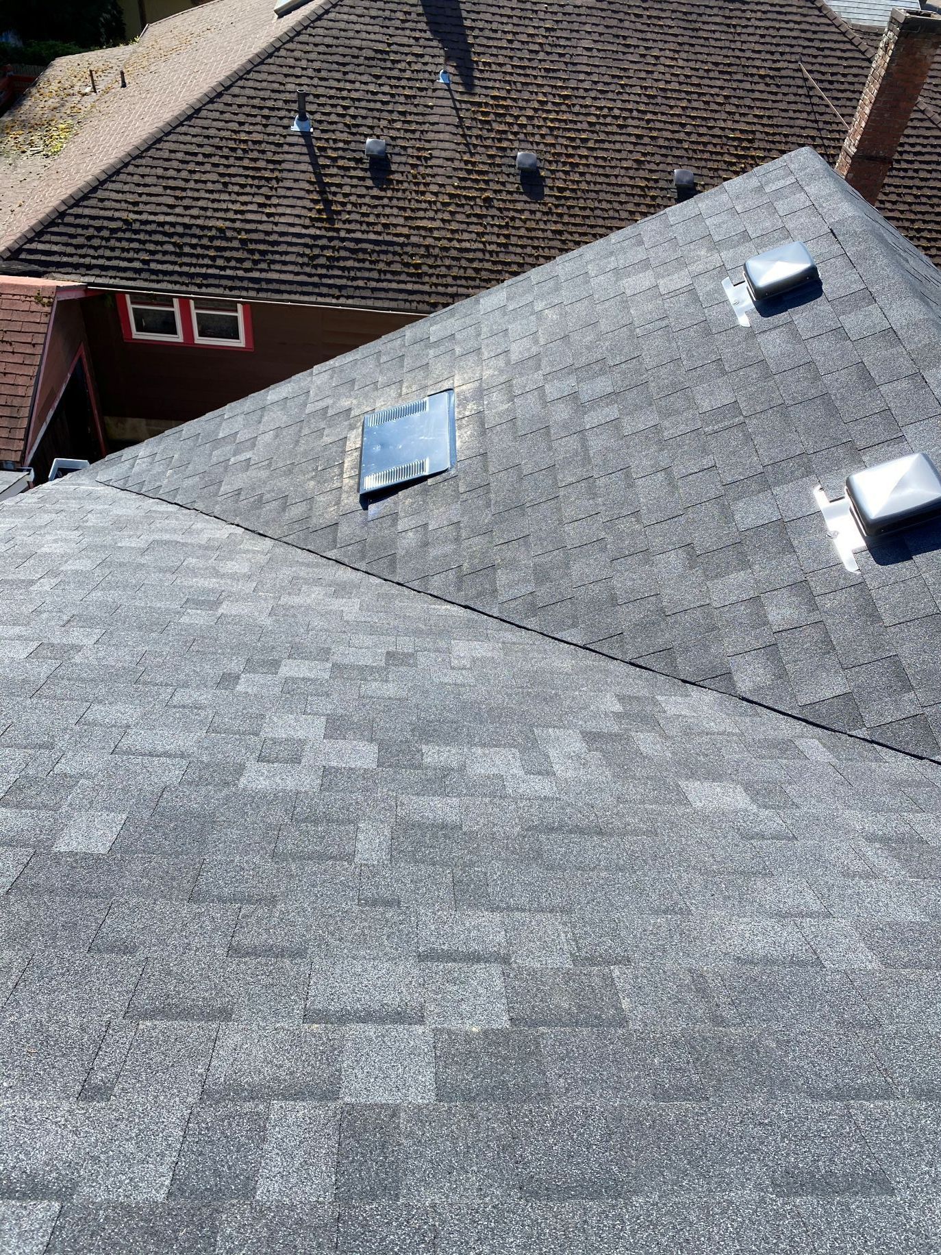 Rooftops with gray shingles and several skylights, viewed from above