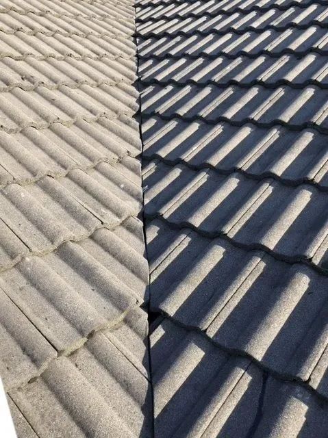 Split view of a gray tiled roof in sunlight and shadow, showing texture and pattern.