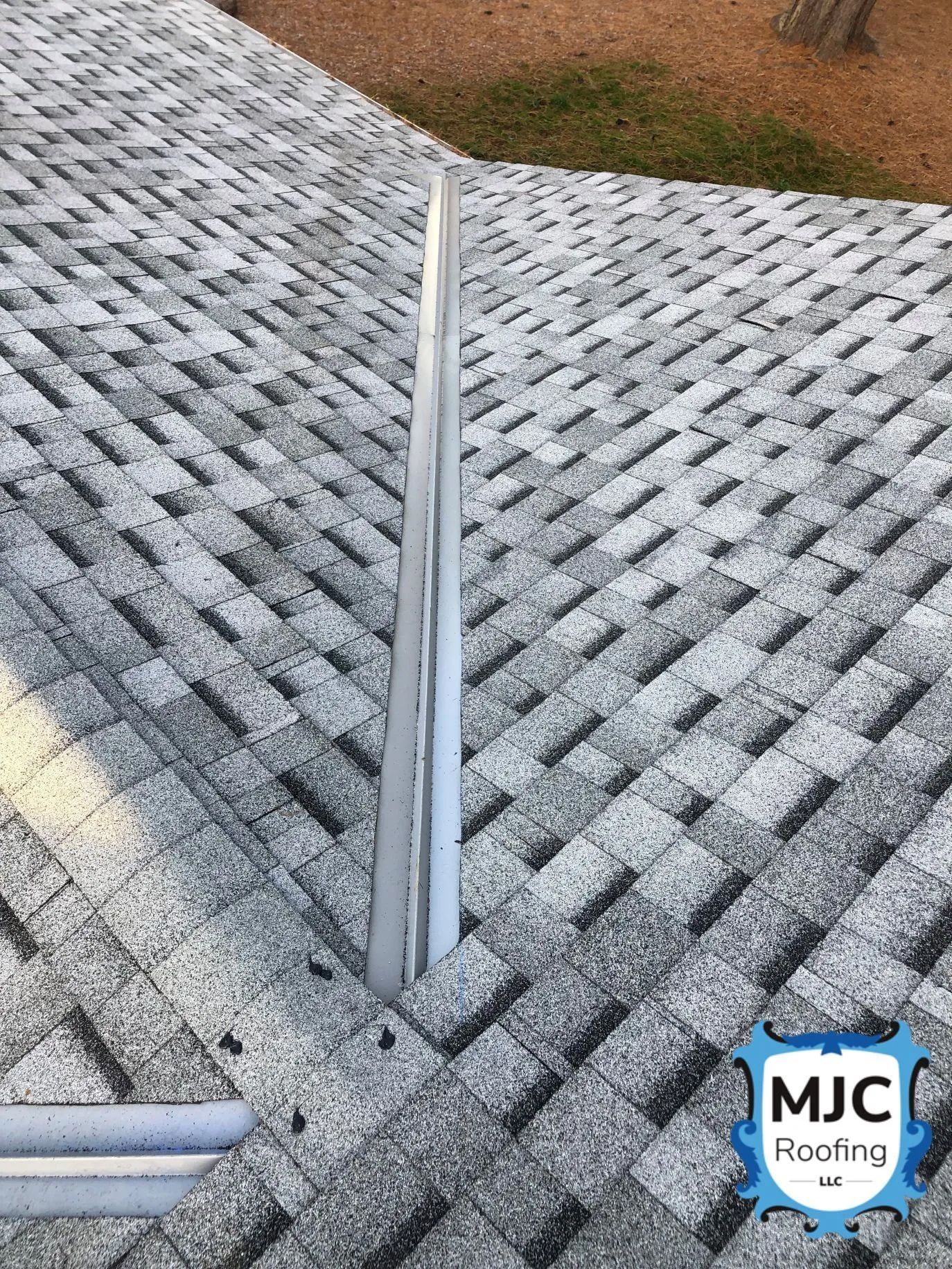 Gray shingle roof with a vertical seam and a roof vent pipe near the edge