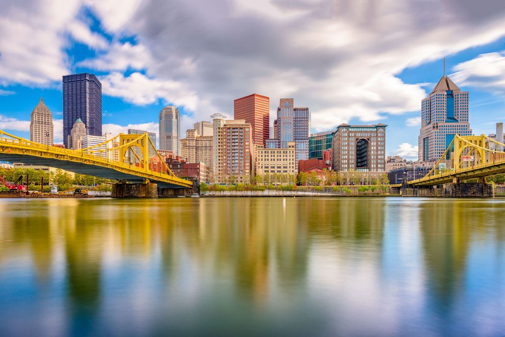 City skyline reflecting in water with yellow bridges.