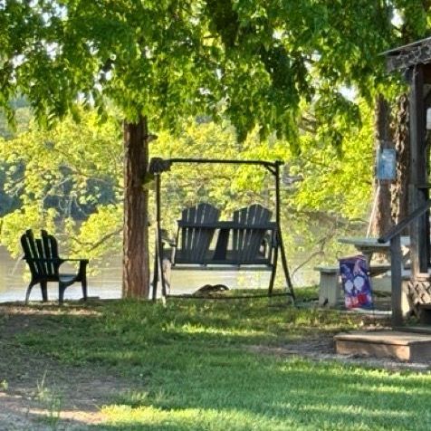 A woman is laying in the grass with her dog.