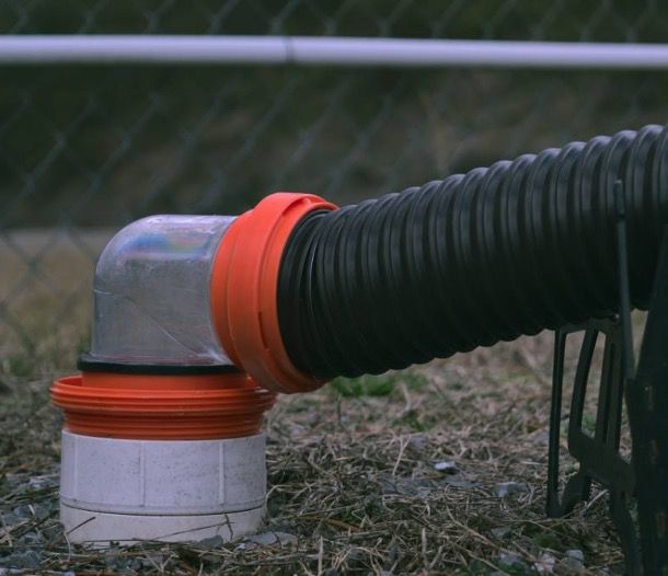 A black pipe with an orange cap is connected to a white pipe