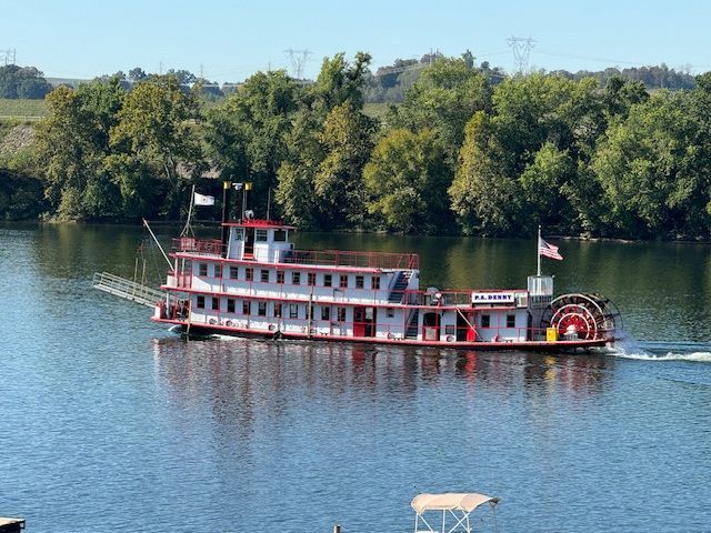 A large boat is floating on a lake with trees in the background.