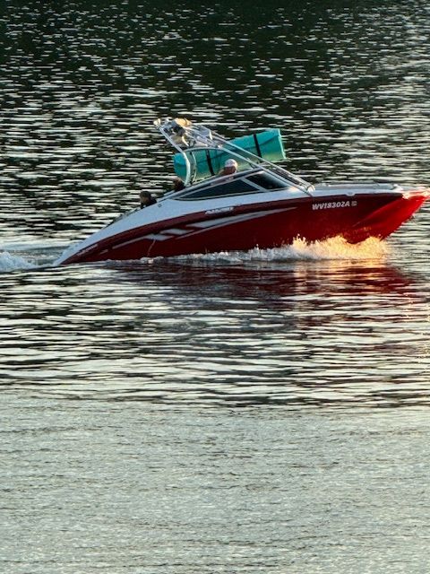 A red and white boat is floating on a lake