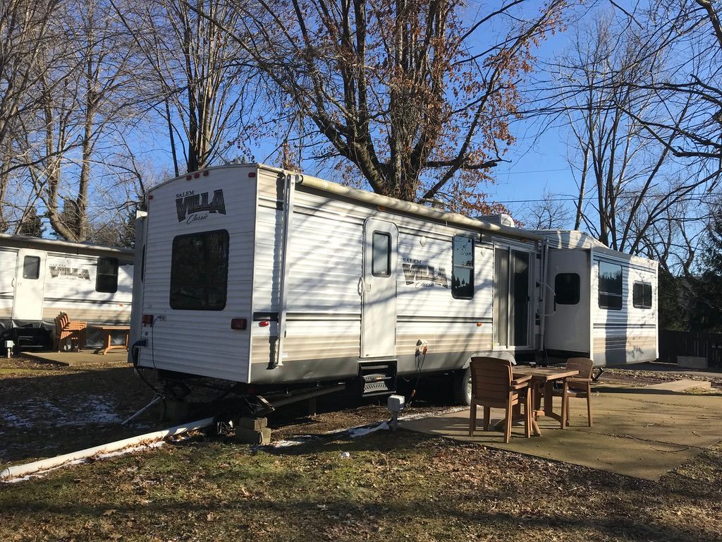 A white rv is parked in a lot with a table and chairs.