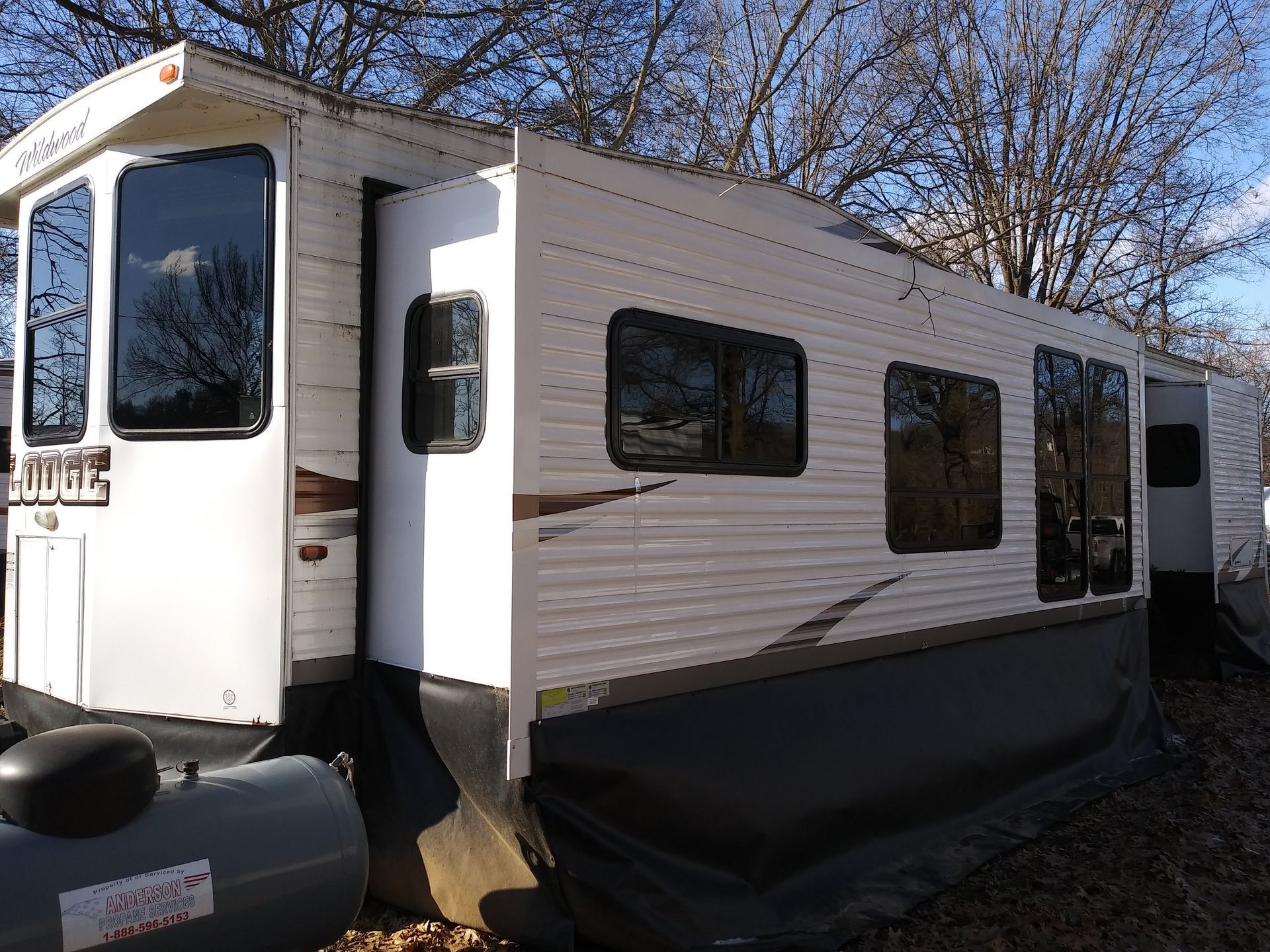 A white rv is parked in a field with trees in the background.