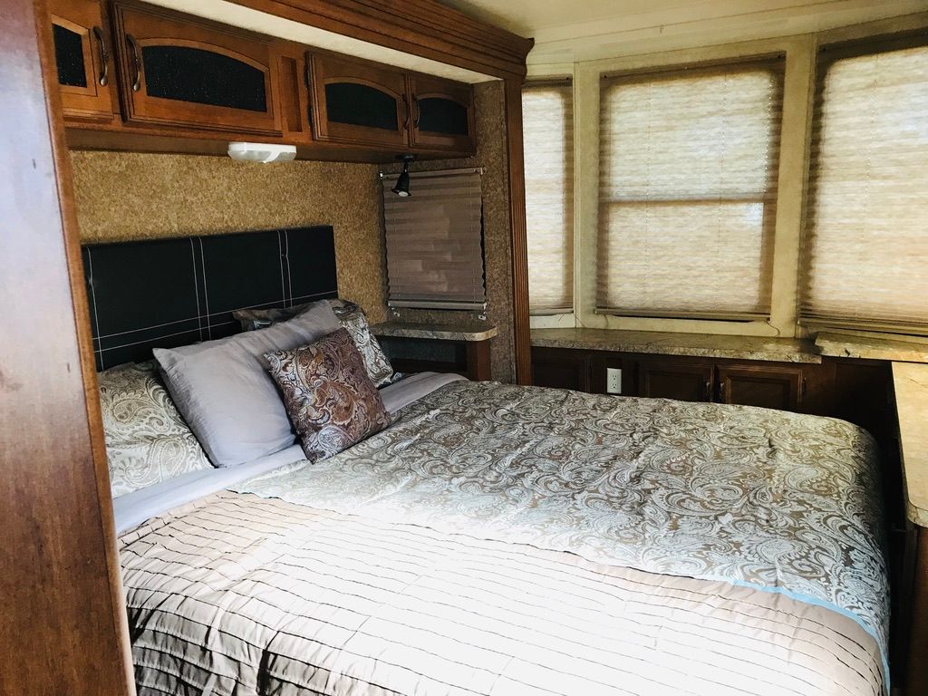 A bedroom in a rv with a large bed and lots of windows.
