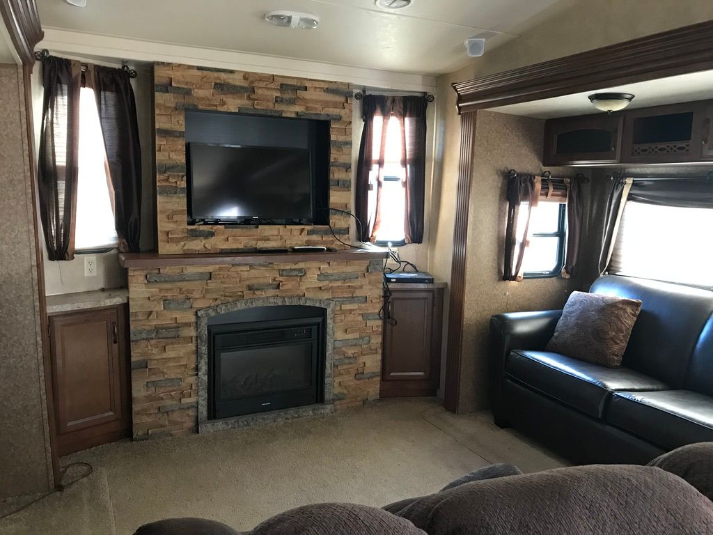 A living room with a couch , fireplace and television.