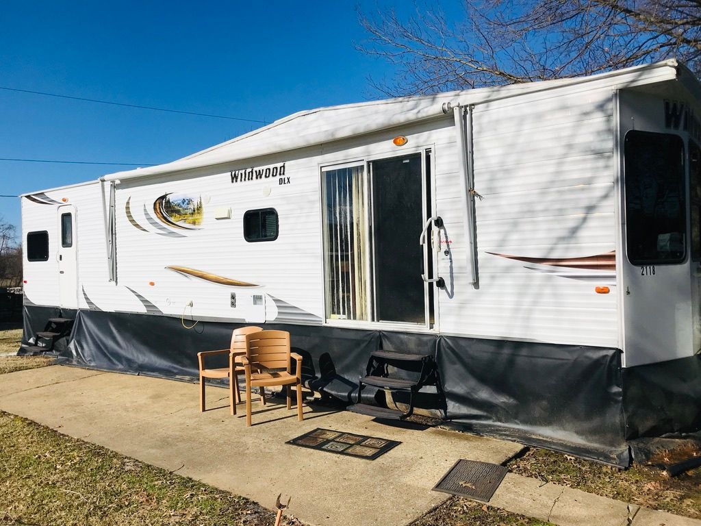 A white rv is parked on the side of the road next to a sidewalk.