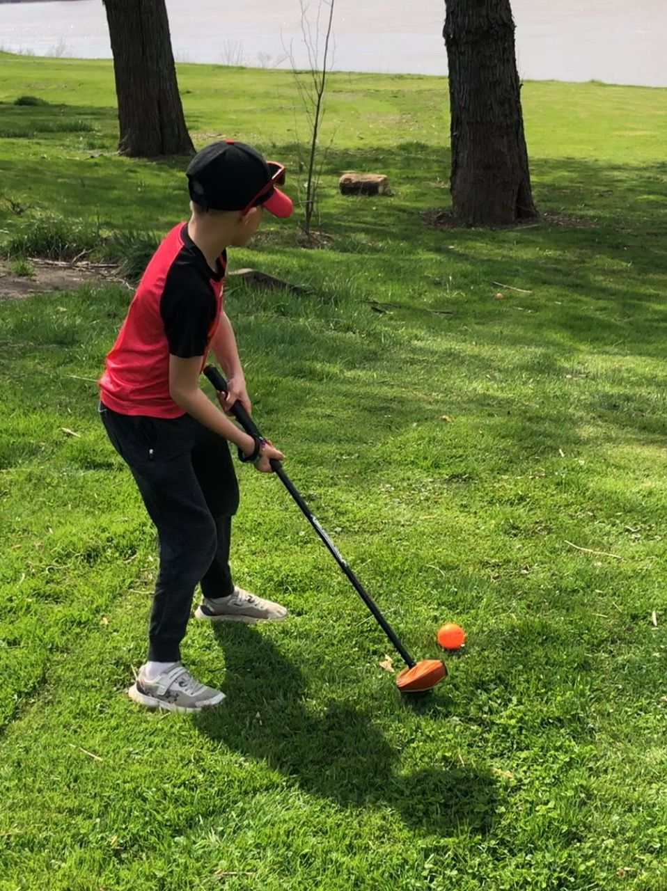 A young boy is playing golf in a park.