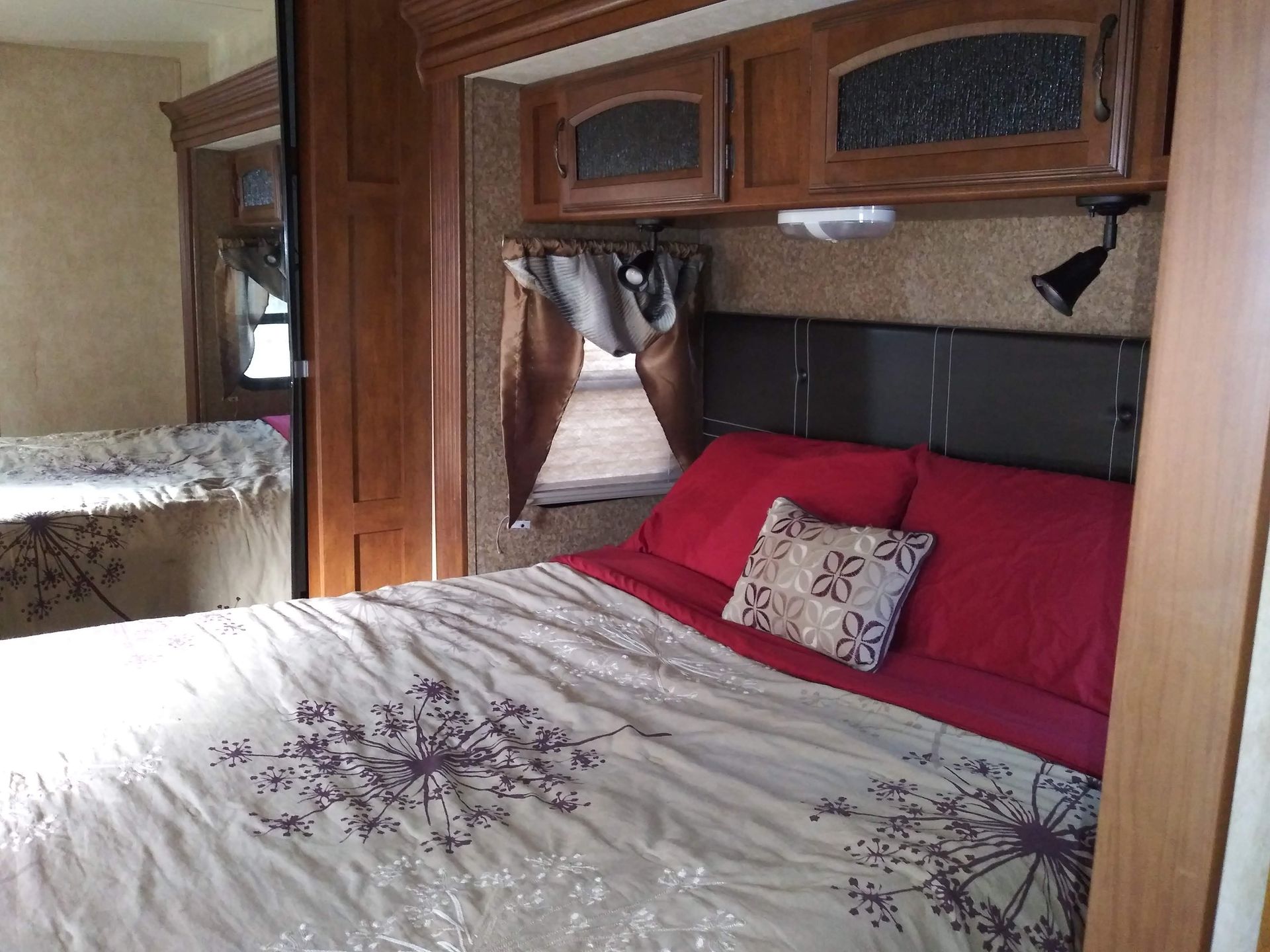 A bedroom in a camper with a bed and red pillows