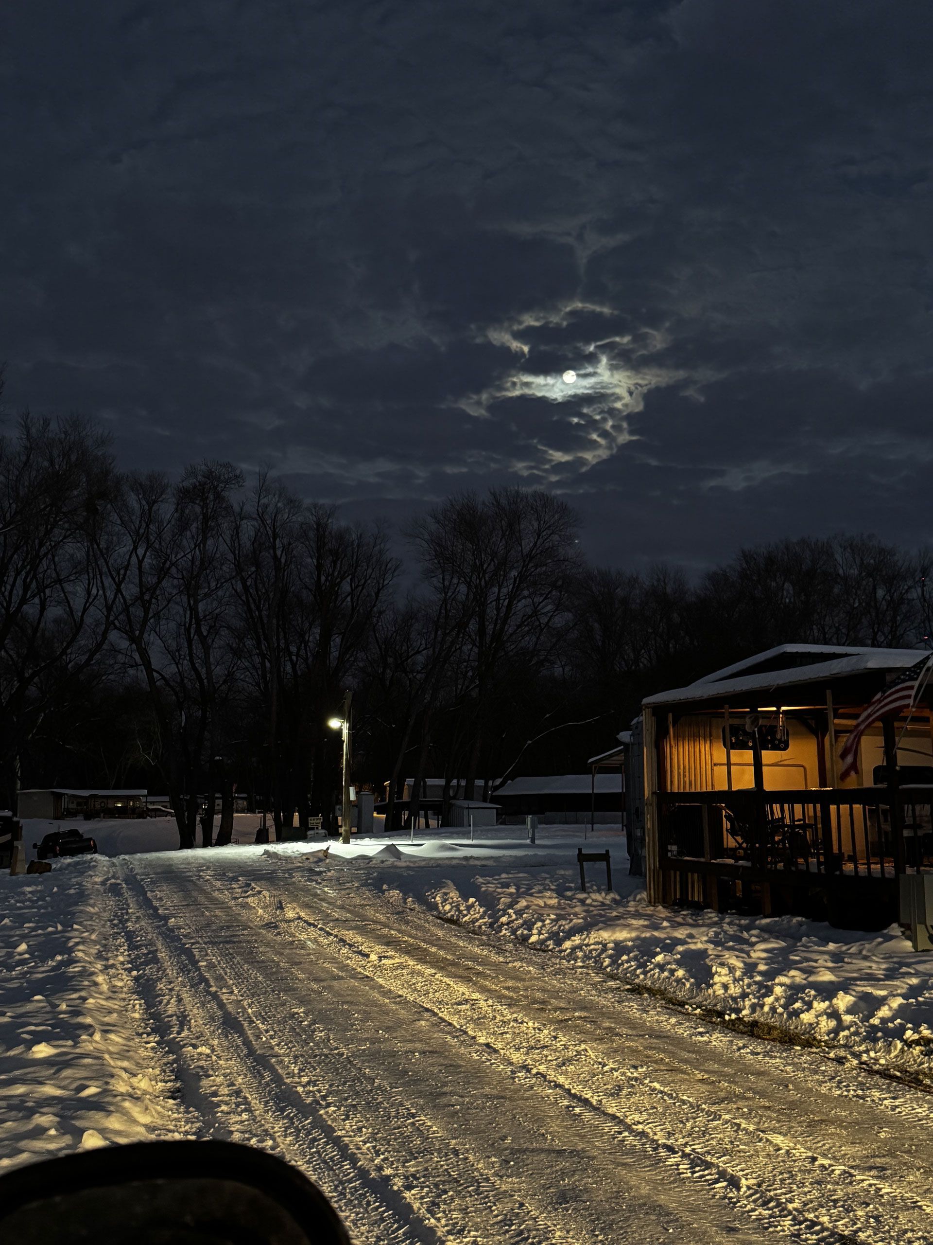 A snowy road at night with a full moon in the sky