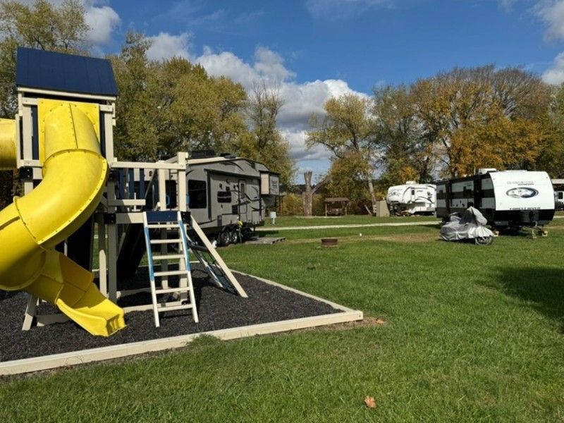 A yellow slide is sitting in the middle of a grassy field.