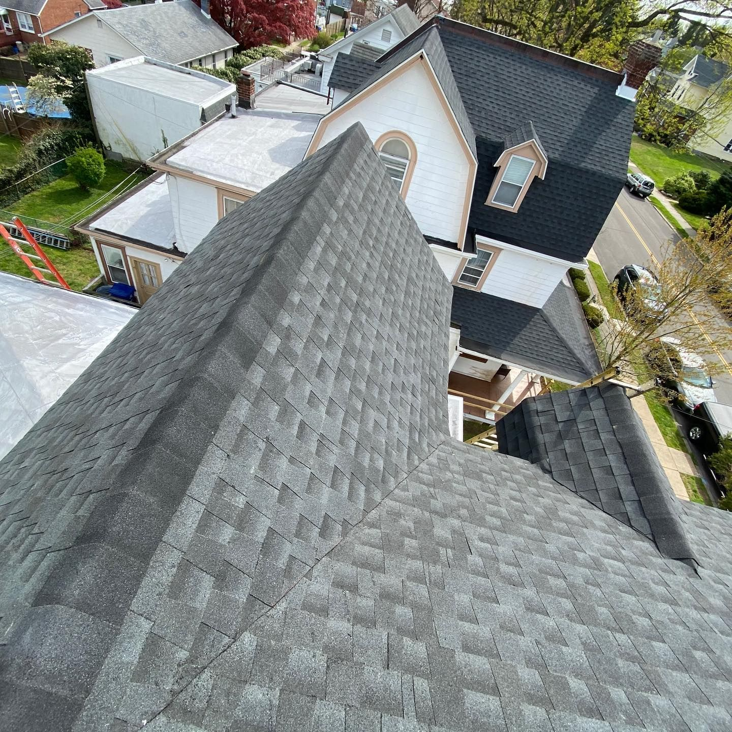 Overhead view of a gray shingled roof on a residential building with a cityscape in the background.